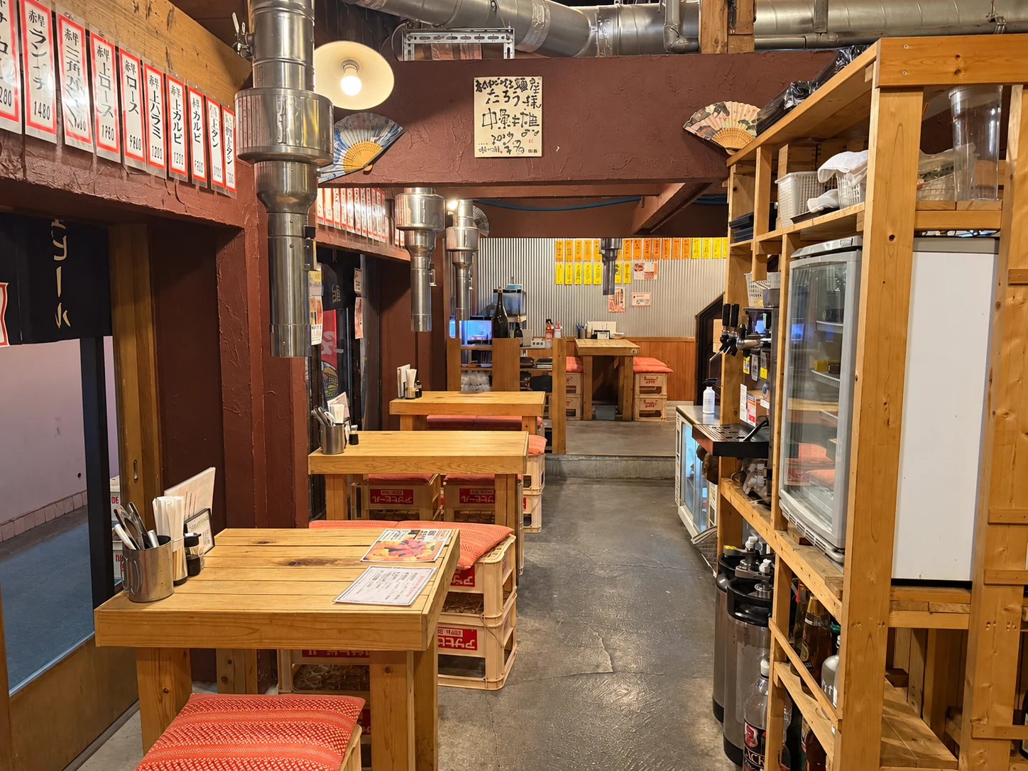 木のテーブルと排気ダクトが並ぶ、昭和レトロな店内